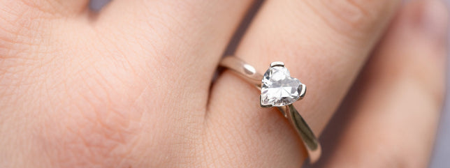 Close up of heart cut solitaire engagement ring worn on hand