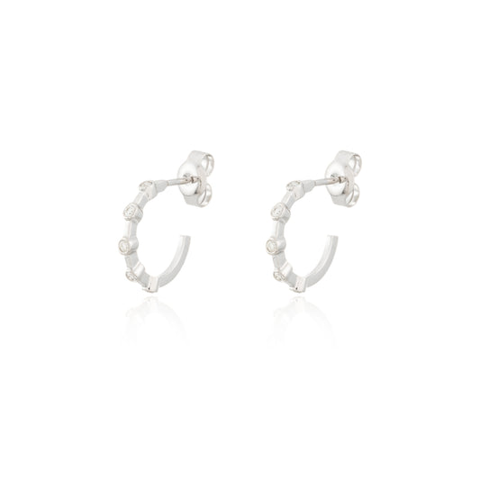 A white render of a pair of white gold huggie hoop stud earrings with diamonds